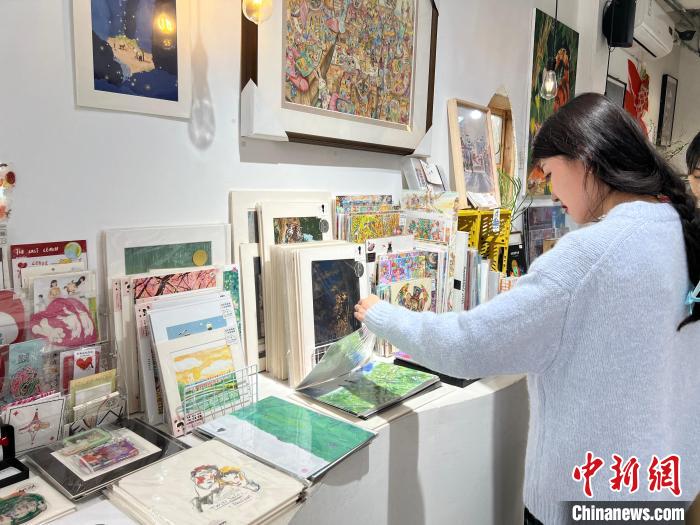 圖為藝術(shù)品商店內(nèi)，顧客挑選插畫作品?！＄婌?攝