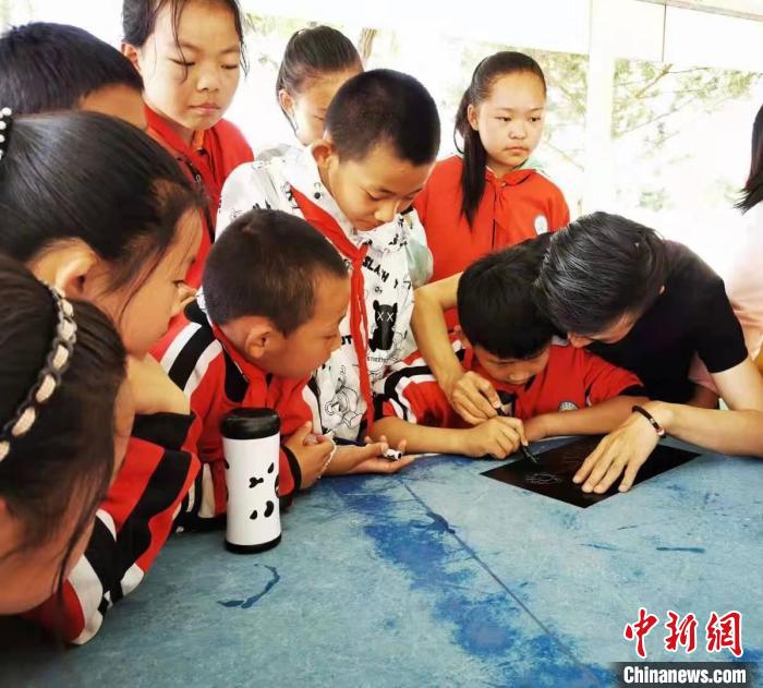 圖為朱增平(右一)教學(xué)生創(chuàng)作鍥金畫。(資料圖) 受訪者供圖