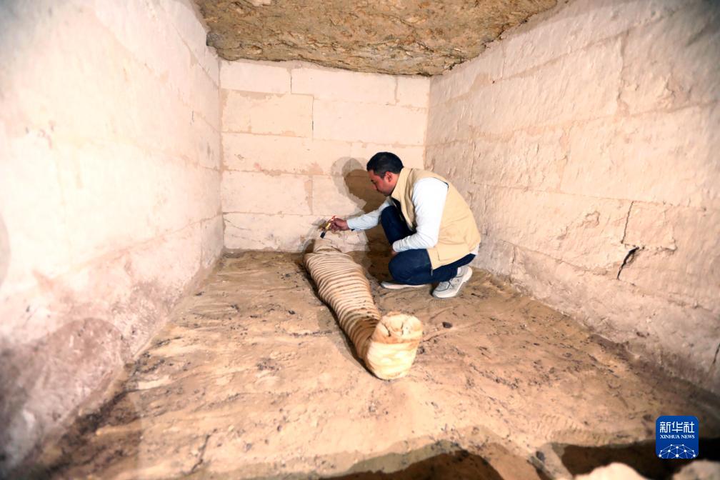 10月15日，在埃及明亞省考古現(xiàn)場，考古人員清理一座石鑿墓中的木乃伊。新華社發(fā)（艾哈邁德·戈馬攝）