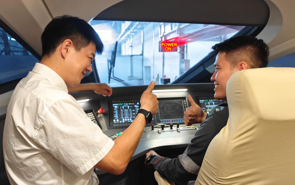 8月25日，在印度尼西亞萬隆的雅萬高鐵德卡魯爾動車所內(nèi)，中國師傅穆振（左）在向印尼火車司機塞蒂亞萬講解動車組出庫前的上電作業(yè)。