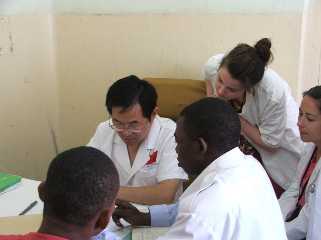 2011年7月22日，在坦桑尼亞桑給巴爾納茲莫加醫(yī)院外科門診，中國(guó)第24批援桑給巴爾醫(yī)療隊(duì)隊(duì)長(zhǎng)盧建林為當(dāng)?shù)鼗颊咴\治并帶教實(shí)習(xí)生。新華社發(fā)（國(guó)家衛(wèi)生健康委供圖）