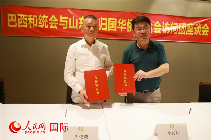 中國(guó)僑聯(lián)副主席、山東省僑聯(lián)主席李興鈺（右）與巴西和統(tǒng)會(huì)會(huì)長(zhǎng)王俊曉簽署合作協(xié)議書(shū)。人民網(wǎng)記者 陳海琪攝