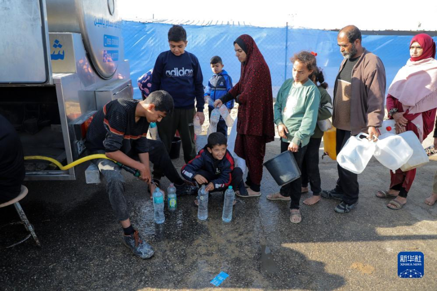 12月8日，在加沙地帶南部城市拉法一處臨時營地內(nèi)，人們排隊打水。新華社發(fā)（里澤克·阿卜杜勒賈瓦德 攝）