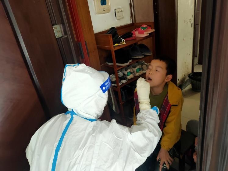 醫(yī)務(wù)工作者為封控區(qū)的居民上門采樣核酸。單位供圖