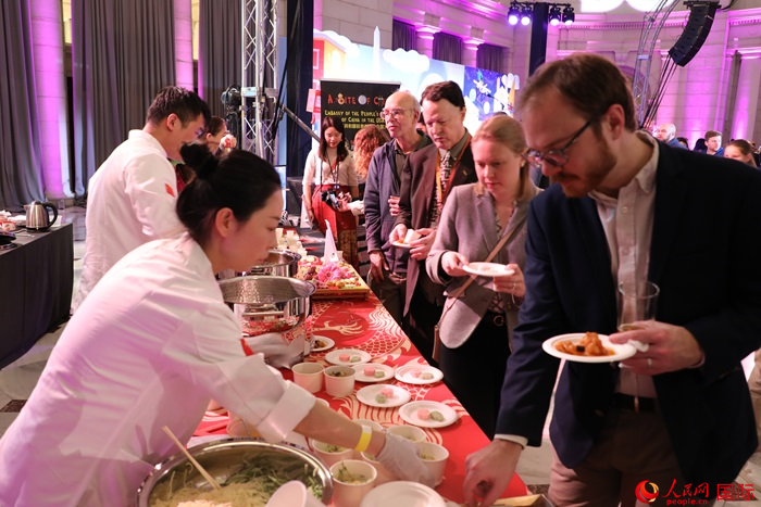 當(dāng)?shù)貢r(shí)間3月7日晚，華盛頓聯(lián)合車站廣場(chǎng)舉行駐美使團(tuán)“使館主廚挑戰(zhàn)賽”。圖為當(dāng)?shù)孛癖娫谥袊?guó)展臺(tái)前體驗(yàn)中國(guó)美食。人民網(wǎng)記者 李志偉攝