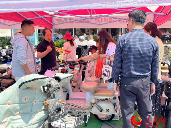 某電動(dòng)自行車(chē)品牌工作人員向消費(fèi)者介紹以舊換新相關(guān)情況。人民網(wǎng)記者 杜燕飛攝