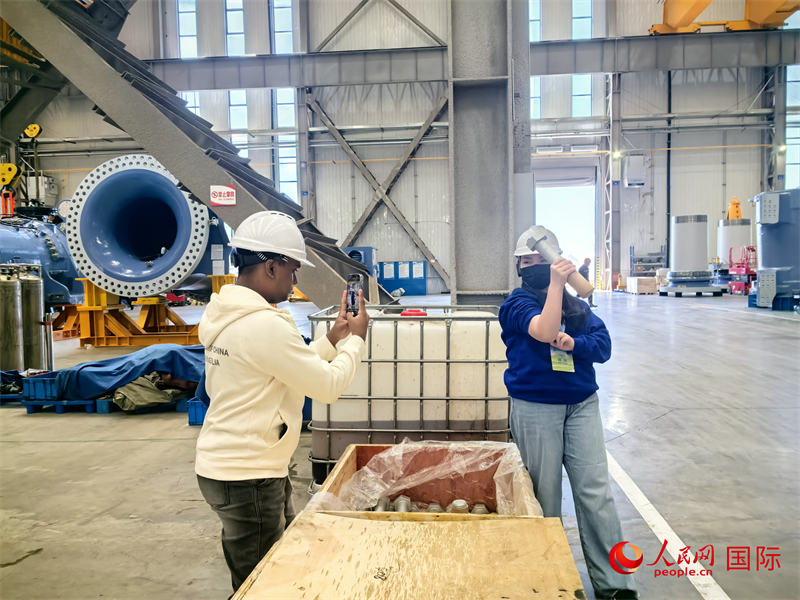 外媒記者掂量廠房內(nèi)的巨型螺栓。人民網(wǎng) 楊春燕攝