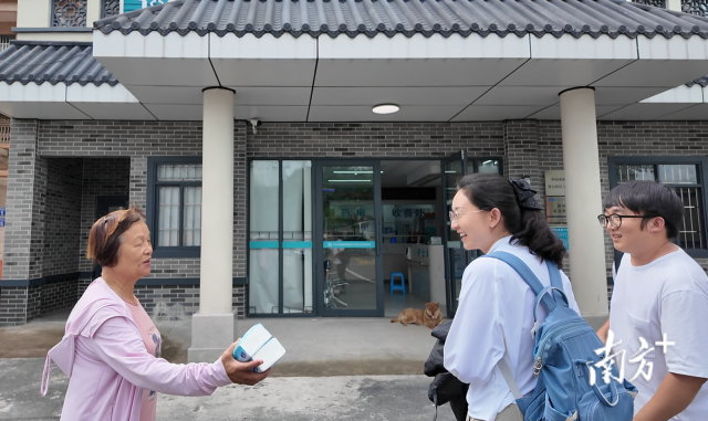 公共服務(wù)組成員王櫻潔（中）和張龍（右）在崖口村衛(wèi)生室前跟村民打招呼。