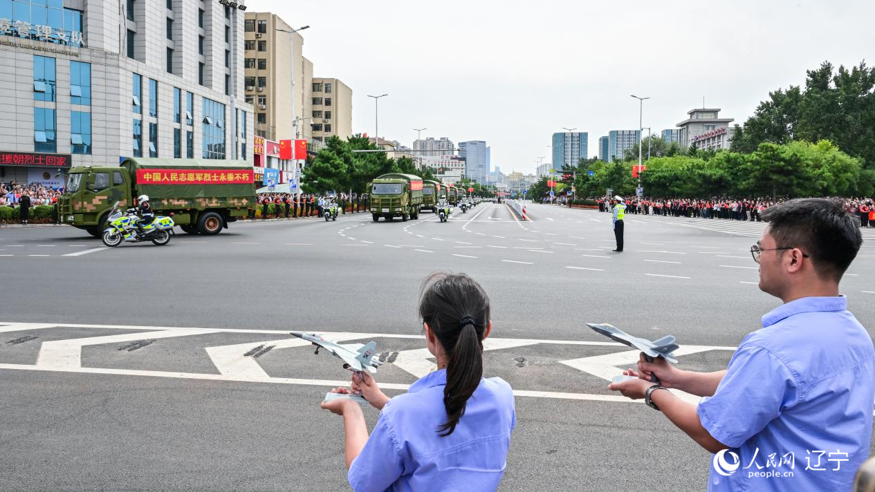 航空工業(yè)沈飛的青年技術(shù)人員拿著受閱戰(zhàn)機(jī)的模型迎接烈士遺骸。航空工業(yè)沈飛供圖