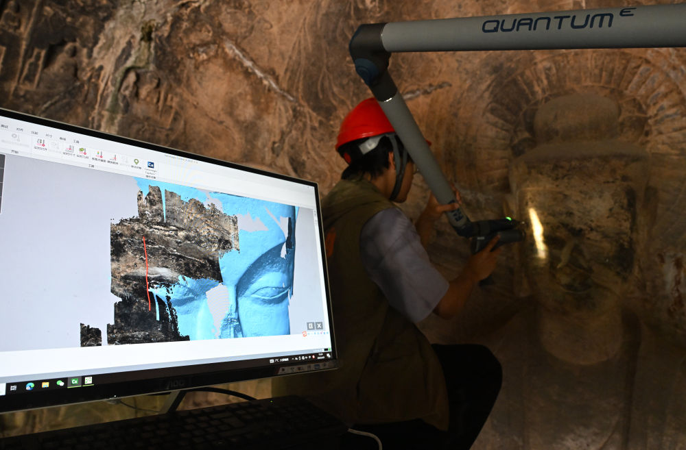 2025年4月9日，武漢大學(xué)文化遺產(chǎn)智能計算實驗室團(tuán)隊成員在魏字洞使用關(guān)節(jié)臂掃描儀對佛像進(jìn)行數(shù)字化掃描。圖片來源新華社