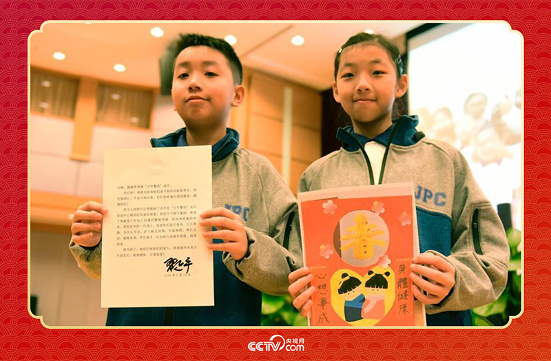 圖為香港“少年警訊”成員郭宏晞（左）展示習(xí)主席回信、羅顥凝（右）展示送給習(xí)主席的賀卡并合影。