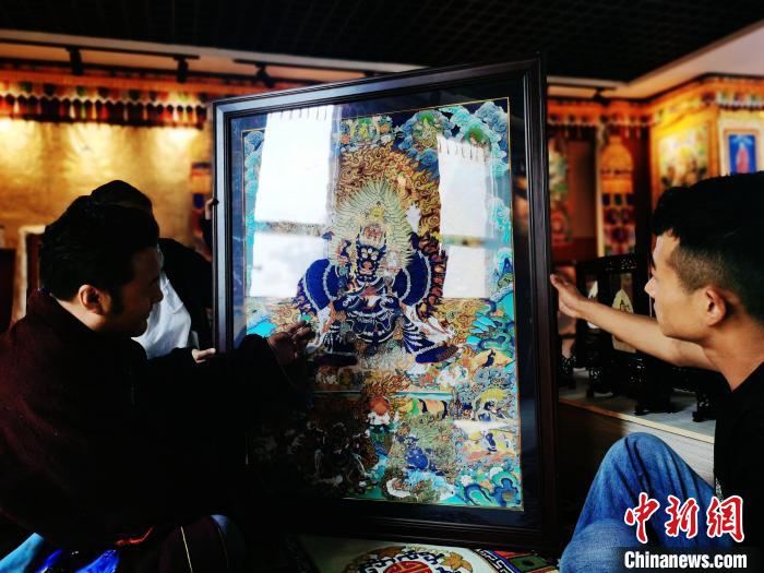 圖為久美尖措(左)與徒弟們展示唐卡作品?！?zhí)砀?攝