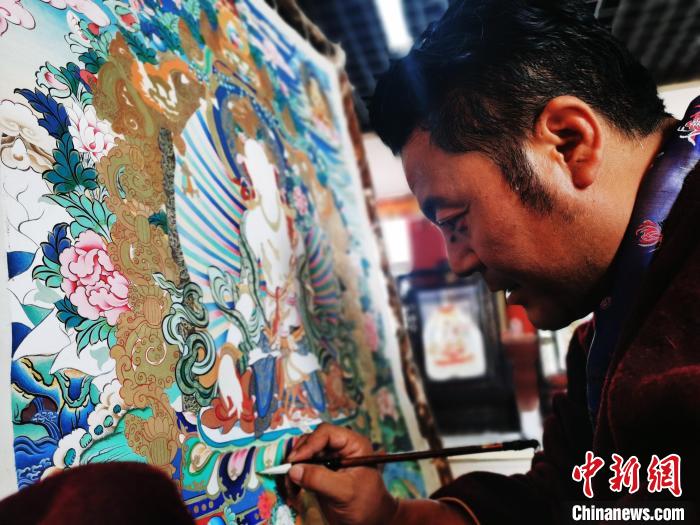 圖為久美尖措創(chuàng)作唐卡?！?zhí)砀?攝