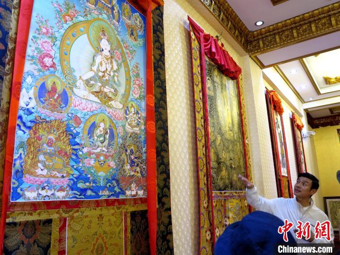圖為完德尖措展示熱貢龍樹畫苑內(nèi)的唐卡?！?zhí)砀?攝