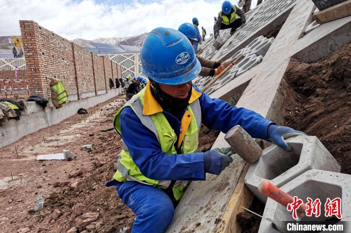 圖為光伏發(fā)電項(xiàng)目施工區(qū)工人在護(hù)坡鋪設(shè)空心磚?！±铍h 攝