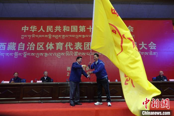 西藏自治區(qū)副主席甲熱·洛桑丹增授代表團團旗，西藏自治區(qū)體育局局長尼瑪次仁接旗。　冉文娟 攝