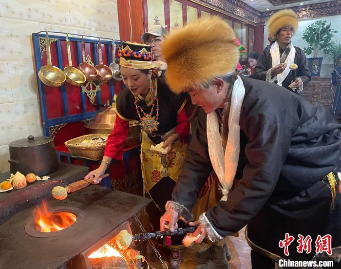 圖為人們在火上烤節(jié)日美食“結(jié)達(dá)”?！∪轿木?攝