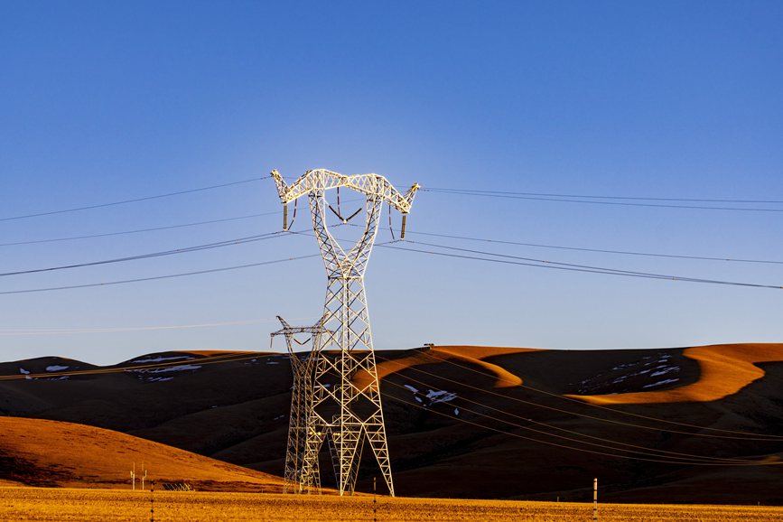 阿里地區(qū)的曠野上，電力鐵塔在夕陽下熠熠生輝。
