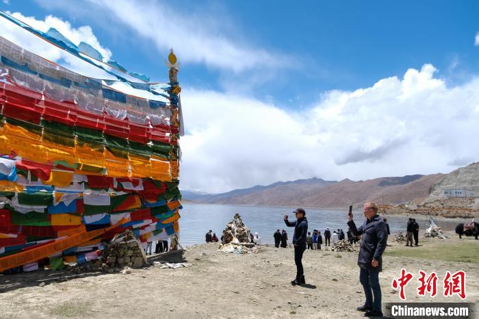 進(jìn)藏參訪嘉賓在羊湖畔拍攝經(jīng)幡。　江飛波 攝