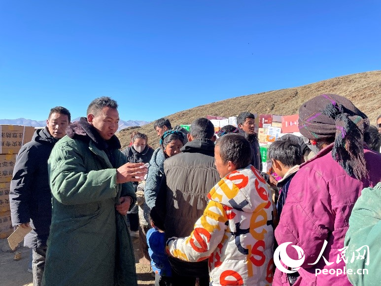 定日縣公安局干警頓珠次仁（左二）正在協(xié)助分發(fā)物資。人民網(wǎng)記者 郝潔攝