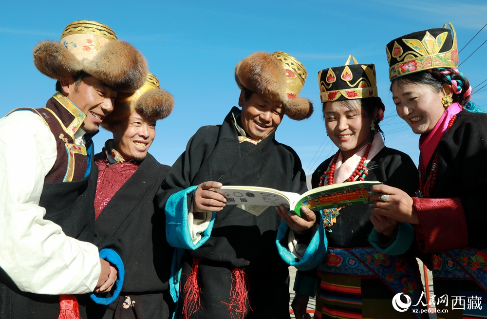 鄉(xiāng)親們身著民族盛裝，圍站在一起認(rèn)真翻看日歷，共話農(nóng)事安排與時(shí)節(jié)規(guī)律，笑容洋溢傳遞豐收期盼。人民網(wǎng)記者 吳雨仁攝