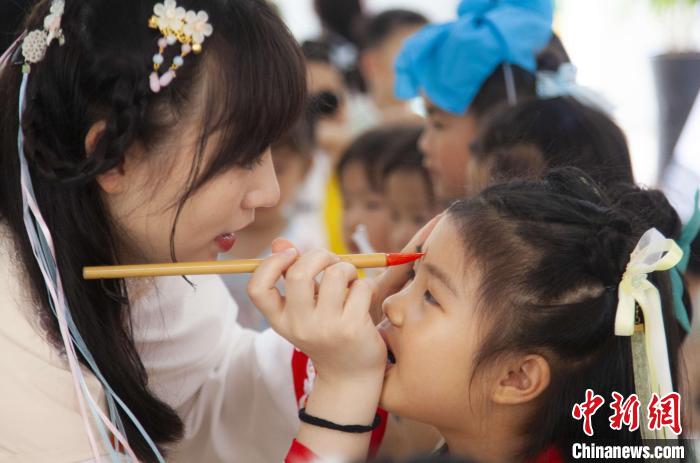 圖為老師在孩子們額頭上點(diǎn)上雄黃，驅(qū)邪辟禍?！《^生 攝